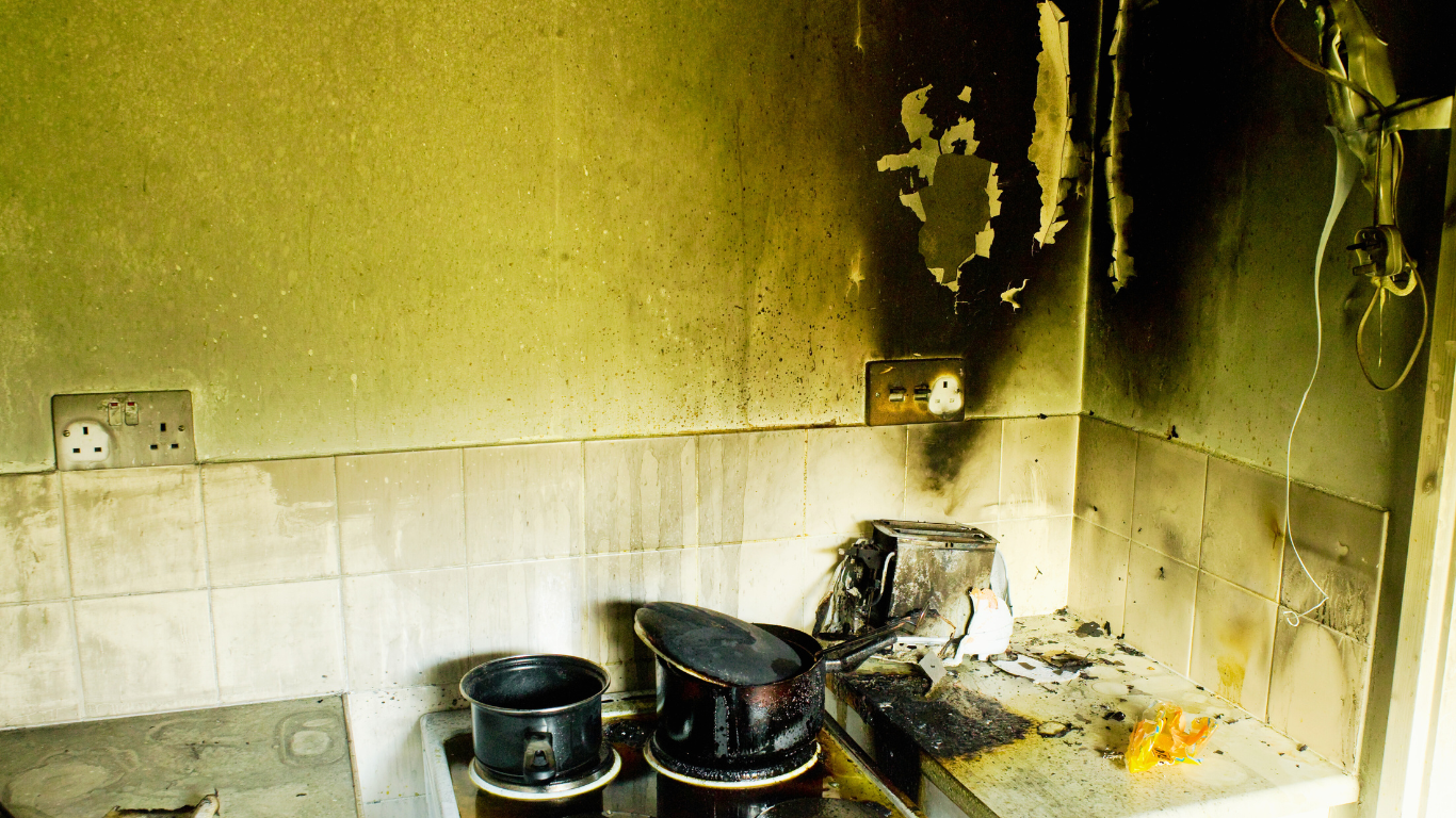 A burned kitchen shows scorched walls, soot-covered appliances, and charred debris—revealing the destructive aftermath and hidden risks of fire damage.