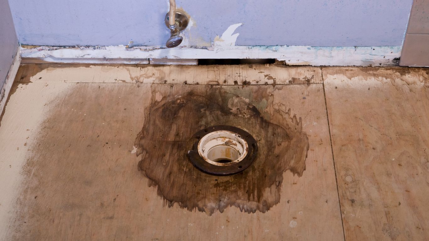 When Should You Call for Water Damage Restoration Services Bathroom floor with severe water damage and rotting wood, showing the need for water damage restoration.